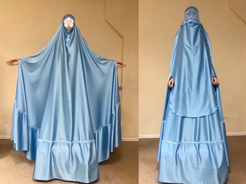 May include: A light blue satin abaya with a lace trim and a long, flowing skirt. The abaya is worn over a matching headscarf.