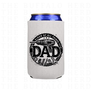 May include: White can cooler with a black graphic that reads "FIXER OF ALL THINGS DAD" with a drill, tools, and a circular design. The can cooler is designed to keep beverages cold.