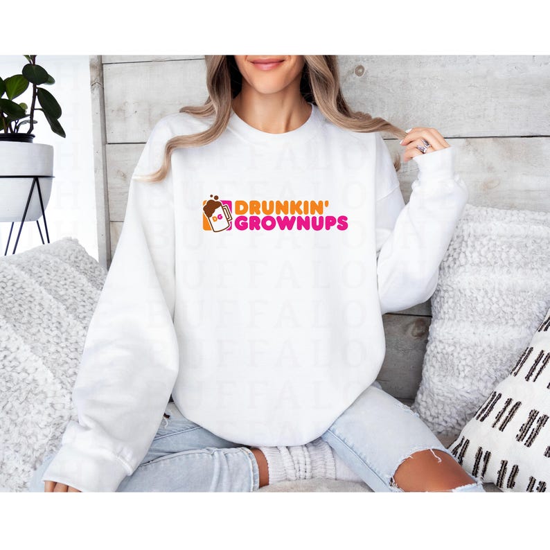 K&ouml;nnte beinhalten: Wei&szlig;er Pullover mit einer pinkfarbenen und orangenen Grafik, auf der "Drunkin' Grownups" steht, mit einem stilisierten Bild einer Kaffeetasse.