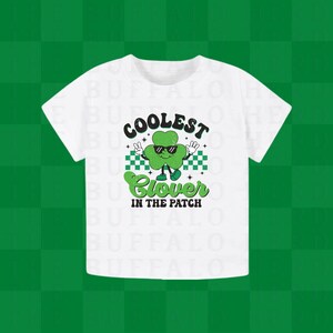 Puede incluir: Camiseta blanca con un trébol verde que lleva gafas de sol y el texto "Coolest Clover in the Patch".