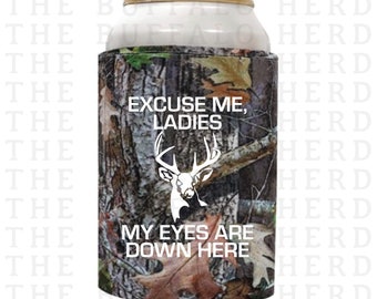 May include: A camouflage can cooler with the text "Excuse me, ladies. My eyes are down here." and a white silhouette of a deer with antlers.