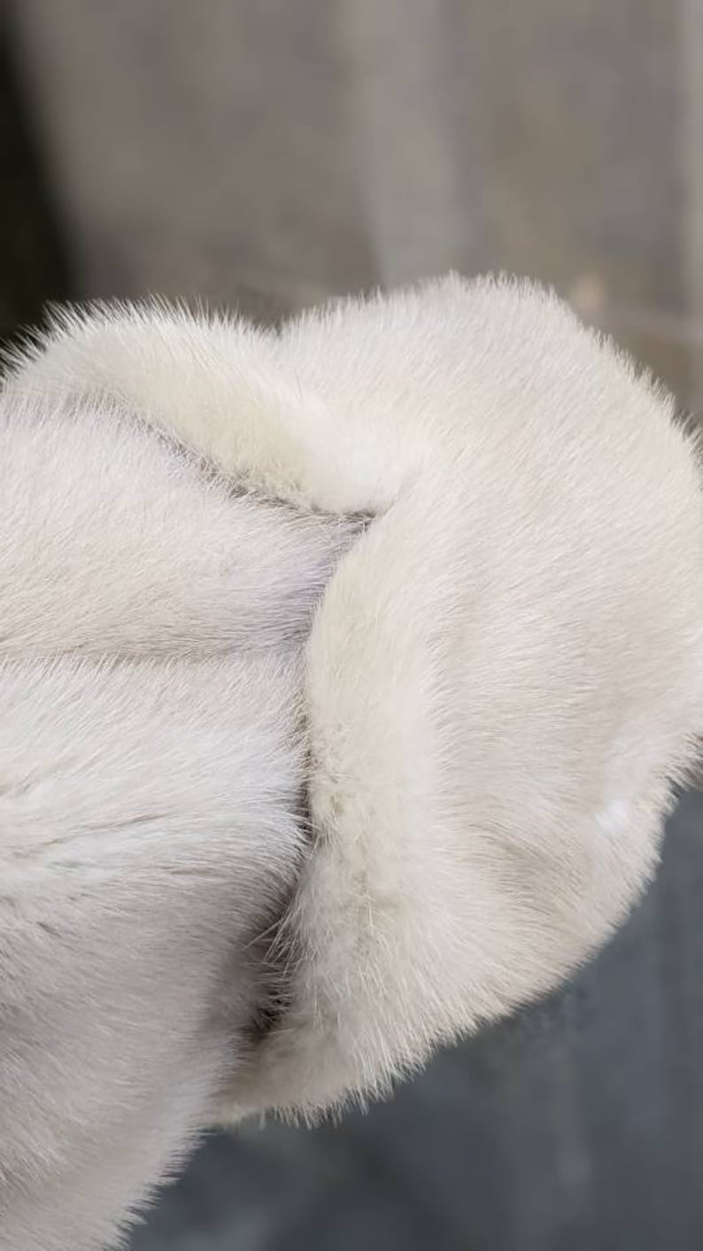 May include: Close-up of a white fur hat with a soft, fluffy texture.