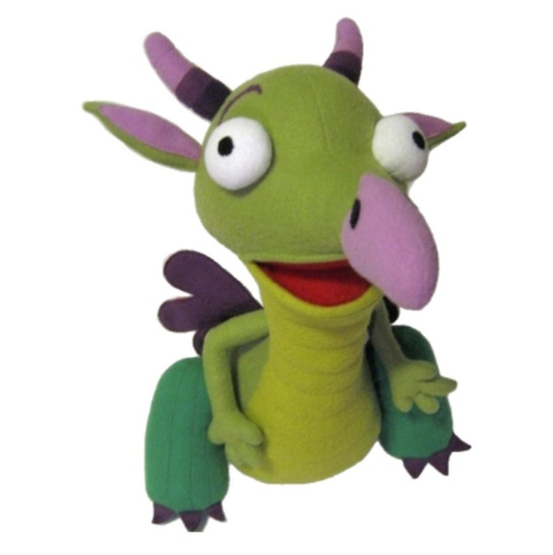 Puede incluir: T&iacute;tere de drag&oacute;n verde con ojos blancos grandes, nariz rosa y boca roja. El drag&oacute;n tiene cuernos, alas y pies morados. Este juguete de peluche est&aacute; dise&ntilde;ado para el juego y el entretenimiento de los ni&ntilde;os.
