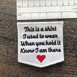 May include: White embroidered patch with black text that reads "This is a shirt I used to wear When you hold it Know I am there" and a red heart in the center.