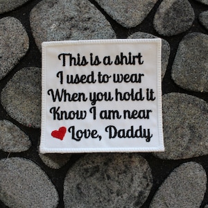 Peut inclure: Patch en tissu blanc avec du texte brodé en noir qui dit "This is a shirt I used to wear When you hold it Know I am near Love, Daddy" avec un cœur rouge.