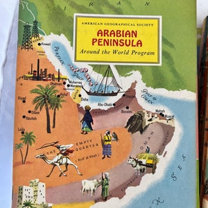 Puede incluir: Portada de libro vintage titulada "Arabian Peninsula" del "Around the World Program" de la American Geographical Society. La portada presenta un mapa ilustrado colorido de la Península Arábiga, con ciudades, puntos de referencia e ilustraciones.
