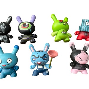 May include: Set of eight colorful, cartoon-style rabbit figurines. The rabbits are all different colors and have unique designs. Some have painted details, such as eyes, mouths, and clothing.