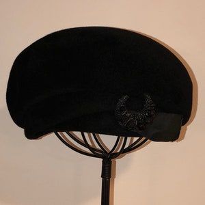 May include: A black felt beret with a black beaded embellishment on the side.