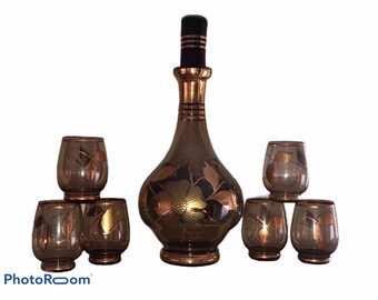 May include: A set of six brown glass decanters with gold accents and floral designs. The decanters are arranged in a pyramid shape, with the largest decanter at the top and the smallest decanters at the bottom.