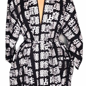 May include: Black and white Japanese-style robe with a V-neck and long sleeves. The robe is covered in white kanji characters on a black background.