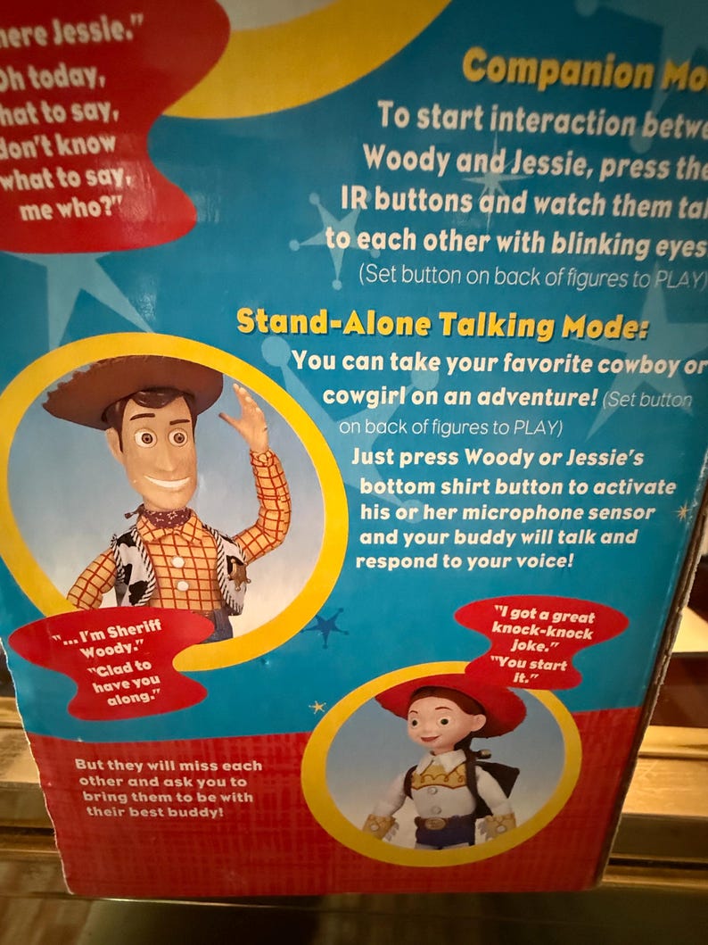 Puede incluir: Caja de producto con ilustraciones de Woody y Jessie de Toy Story. El texto describe funciones interactivas y un modo de conversaci&oacute;n independiente. Woody lleva un sombrero y chaleco de vaquero. Jessie lleva un sombrero rojo.