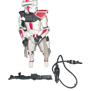 May include: A white and red Star Wars action figure of a clone trooper with a black blaster rifle and a black rope.