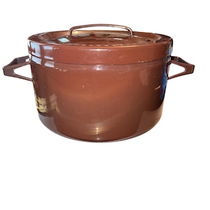 May include: A brown, lidded cooking pot with two side handles and a handle on the lid. The pot has a glossy finish and a rounded shape. The pot is designed for cooking and food preparation.