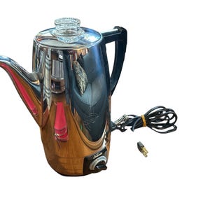 May include: A vintage chrome coffee percolator with a black handle and a glass top. The electric coffee maker has a spout, a power cord, and a dial. The Sunbeam brand percolator is a classic kitchen appliance.