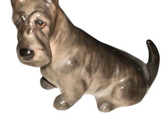 Peut inclure: Une petite figurine en céramique grise d'un chien terrier écossais assis, les oreilles dressées.