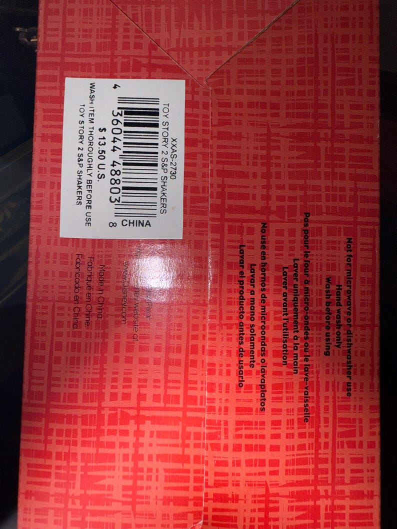 May include: Red box with a grid pattern. The box contains text that reads "TOY STORY 2 S&P SHAKERS" and "WASH ITEM THOROUGHLY BEFORE USE". There is a barcode and the text "CHINA".
