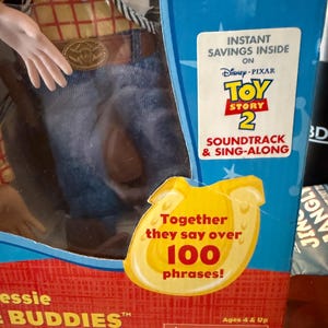 Puede incluir: Una figura de Jessie de Toy Story 2 en caja. La caja presenta el logotipo de Disney Pixar, el texto "Soundtrack & Sing-Along" y un gr&aacute;fico amarillo que dice "Together they say over 100 phrases!". La figura lleva una camisa amarilla, vaqueros azules y un cintur&oacute;n marr&oacute;n.