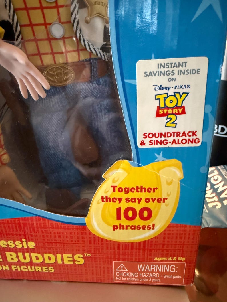 Puede incluir: Una figura de Jessie de Toy Story 2 en caja. La caja presenta el logotipo de Disney Pixar, el texto "Soundtrack & Sing-Along" y un gr&aacute;fico amarillo que dice "Together they say over 100 phrases!". La figura lleva una camisa amarilla, vaqueros azules y un cintur&oacute;n marr&oacute;n.