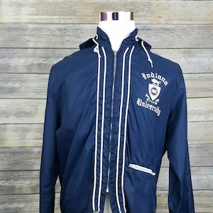 May include: A navy blue hooded jacket with white piping and a white embroidered logo that says "Indiana University".