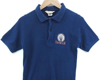 May include: A navy blue short-sleeved polo shirt with an embroidered logo featuring a Native American headdress and the text "Fighting Illini".