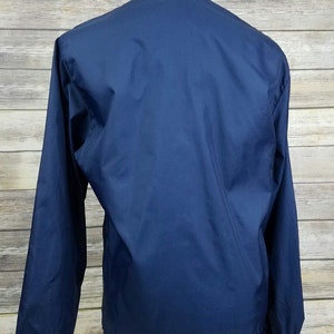 May include: A navy blue windbreaker jacket with a white and navy blue striped collar.