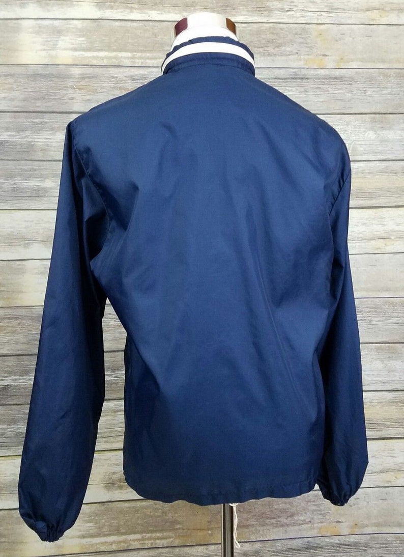 May include: A navy blue windbreaker jacket with a white and navy blue striped collar.