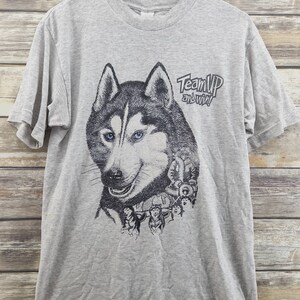 May include: Gray t-shirt with a graphic of a husky dog and the text "Team Up and Win!"