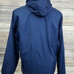 May include: A navy blue hooded jacket with a zipper closure. The jacket is made of a lightweight, water-resistant material.