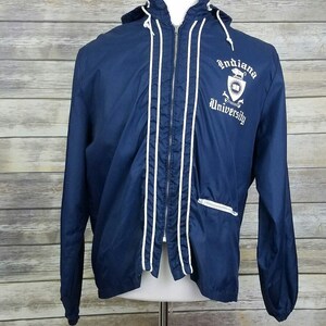 May include: A navy blue hooded jacket with white piping and a white embroidered logo that says "Indiana University".