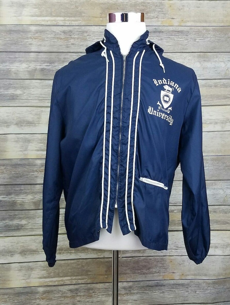 May include: A navy blue hooded jacket with white piping and a white embroidered logo that says "Indiana University".