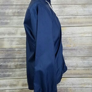 May include: A navy blue windbreaker jacket with white piping along the collar, zipper, and cuffs.