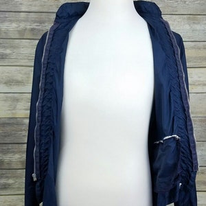 May include: A navy blue lightweight jacket with a zipper closure. The jacket is unzipped and the lining is visible.