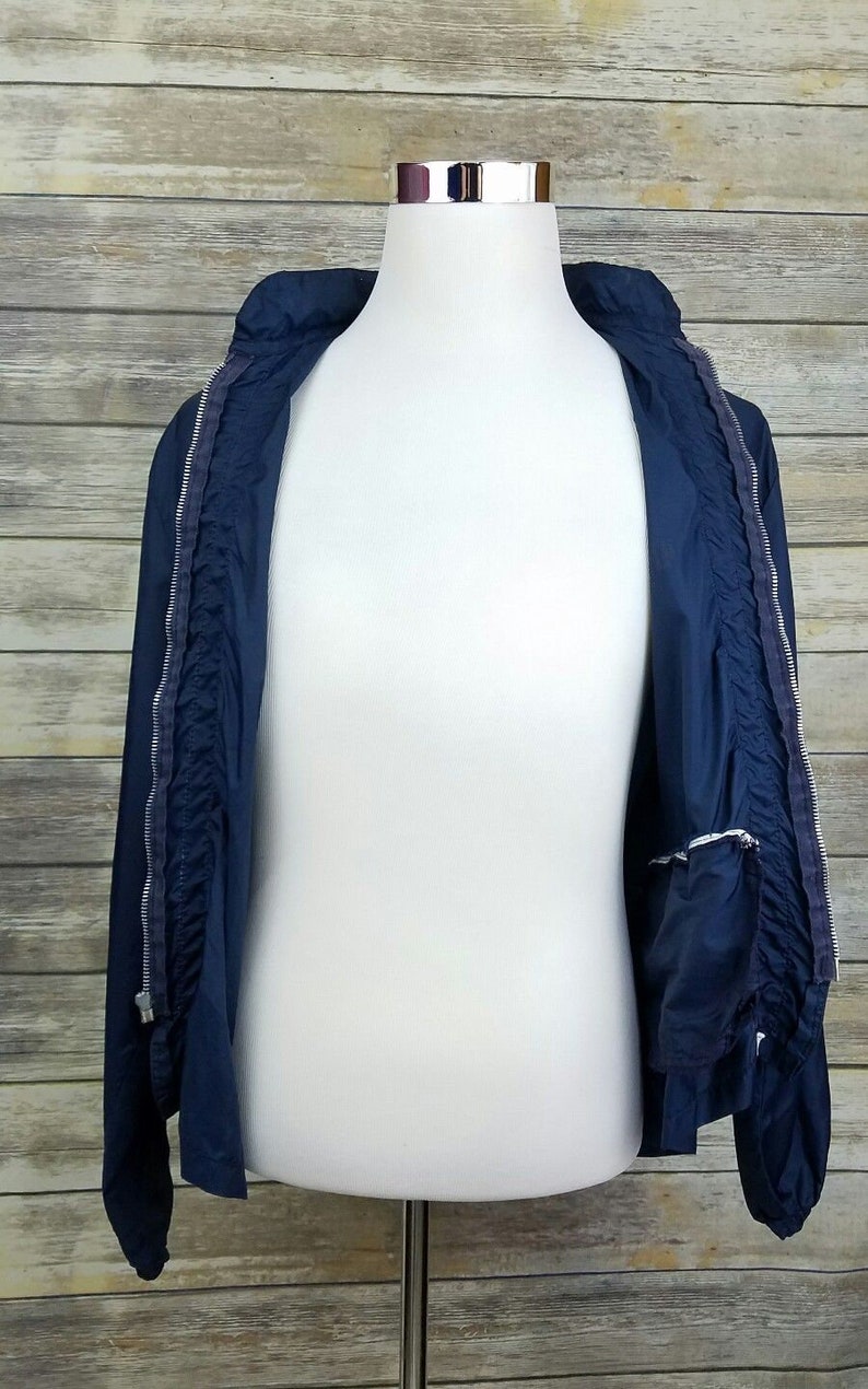 May include: A navy blue lightweight jacket with a zipper closure. The jacket is unzipped and the lining is visible.