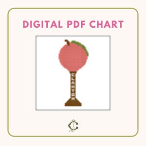 May include: A digital PDF cross-stitch pattern featuring a peach-colored peach with a green leaf on top, sitting on a brown stand with the word "ELKHTON" written on it.