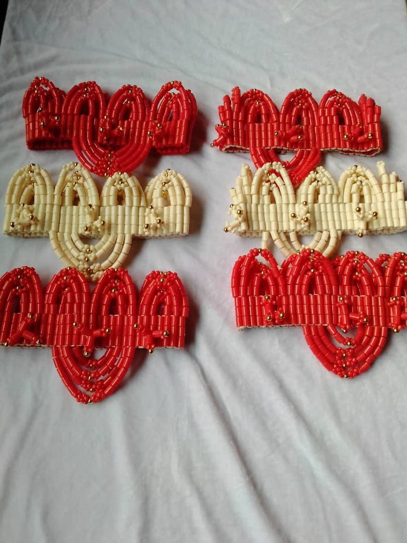 May include: A set of six beaded headbands, three red and three cream colored, with gold beads interspersed throughout. The headbands are arranged in two rows of three, with the red headbands on top and the cream headbands on the bottom.