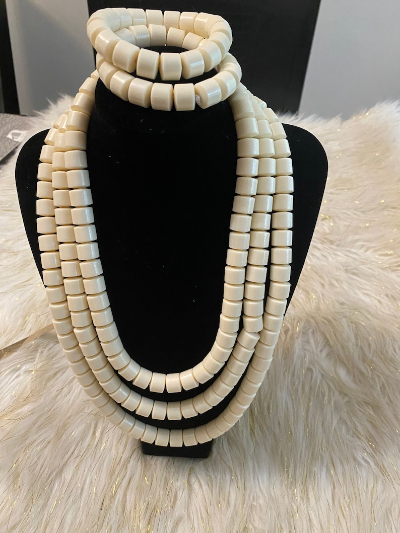 May include: A set of three white beaded necklaces with a matching bracelet. The beads are round and have a smooth, polished finish.