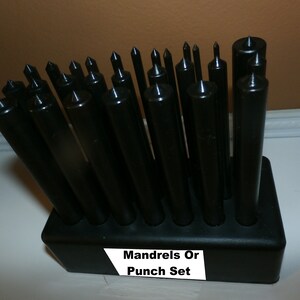 May include: A set of black metal mandrels or punches in a black plastic holder. The holder has a white label that reads "Mandrels Or Punch Set".