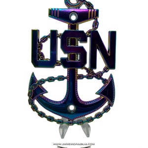 May include: A rainbow iridescent metal US Navy anchor with a chain and the letters USN. The anchor is on a clear acrylic stand.