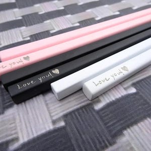 May include: A set of six chopsticks in pink, black, and white, arranged in pairs. Each chopstick features the engraved text "Love you!" followed by a small heart symbol. The chopsticks have a square profile and a smooth, matte finish.