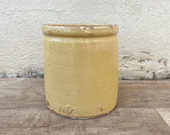 May include: A yellow ceramic jar with a slightly chipped rim and the letter "NV" stamped on the bottom.