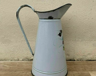 May include: White enamel pitcher with a floral design and a black handle. The pitcher has a slightly pink hue and is in vintage condition.