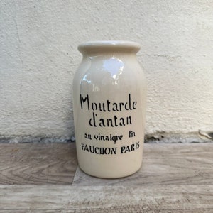 Puede incluir: Tarro de cerámica blanco con letras negras que dicen "Moutarde d'antan au vinaigre fin FAUCHON PARIS".