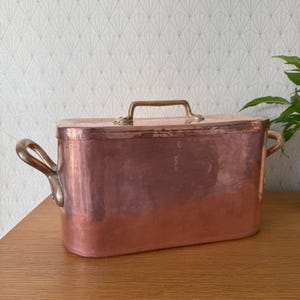Pode incluir: Uma assadeira de cobre vintage com duas alças de latão e uma alça de tampa de latão. A assadeira tem um acabamento martelado e está em bom estado.