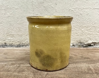 Könnte beinhalten: Eine gelbe Keramikvase mit glasierter Oberfläche. Die Vase hat einen leicht abgenutzten Look mit etwas grünlicher Verfärbung.