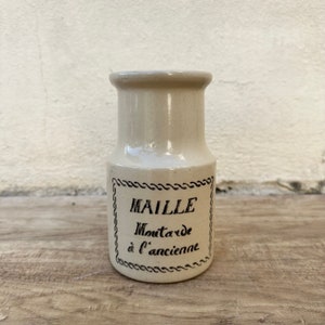 May include: A white ceramic jar with a black label that reads "MAILLE Mustard à l'ancienne".