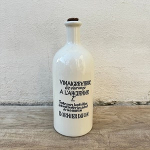 以下が含まれることがあります： 黒いラベルに「VINAIGREVIEUX de vinrouge A L'ANCIENNE 7° Toutes mes bouteilles doivent porter le cachet de ma maison BORNIER DIJON」と書かれた白い陶器のボトル。