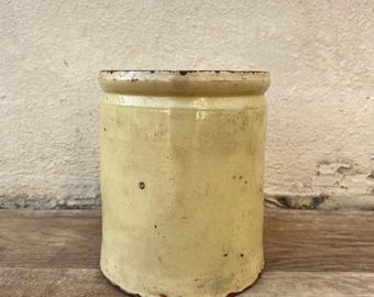 May include: A yellow ceramic jar with a brown rim. The jar has a rustic, vintage look and is slightly weathered.