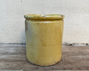 May include: A yellow ceramic jar with a slightly distressed finish. The jar has a rounded shape and a wide mouth.