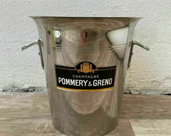 May include: Silver champagne bucket with a black and gold label that reads "Champagne Pommery & Greno".