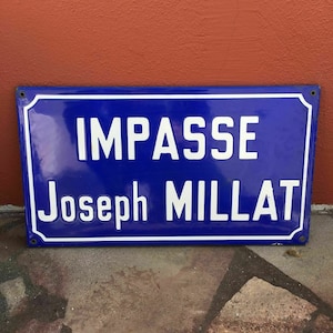 May include: A blue enamel street sign with white lettering that reads "Impasse Joseph Millat".